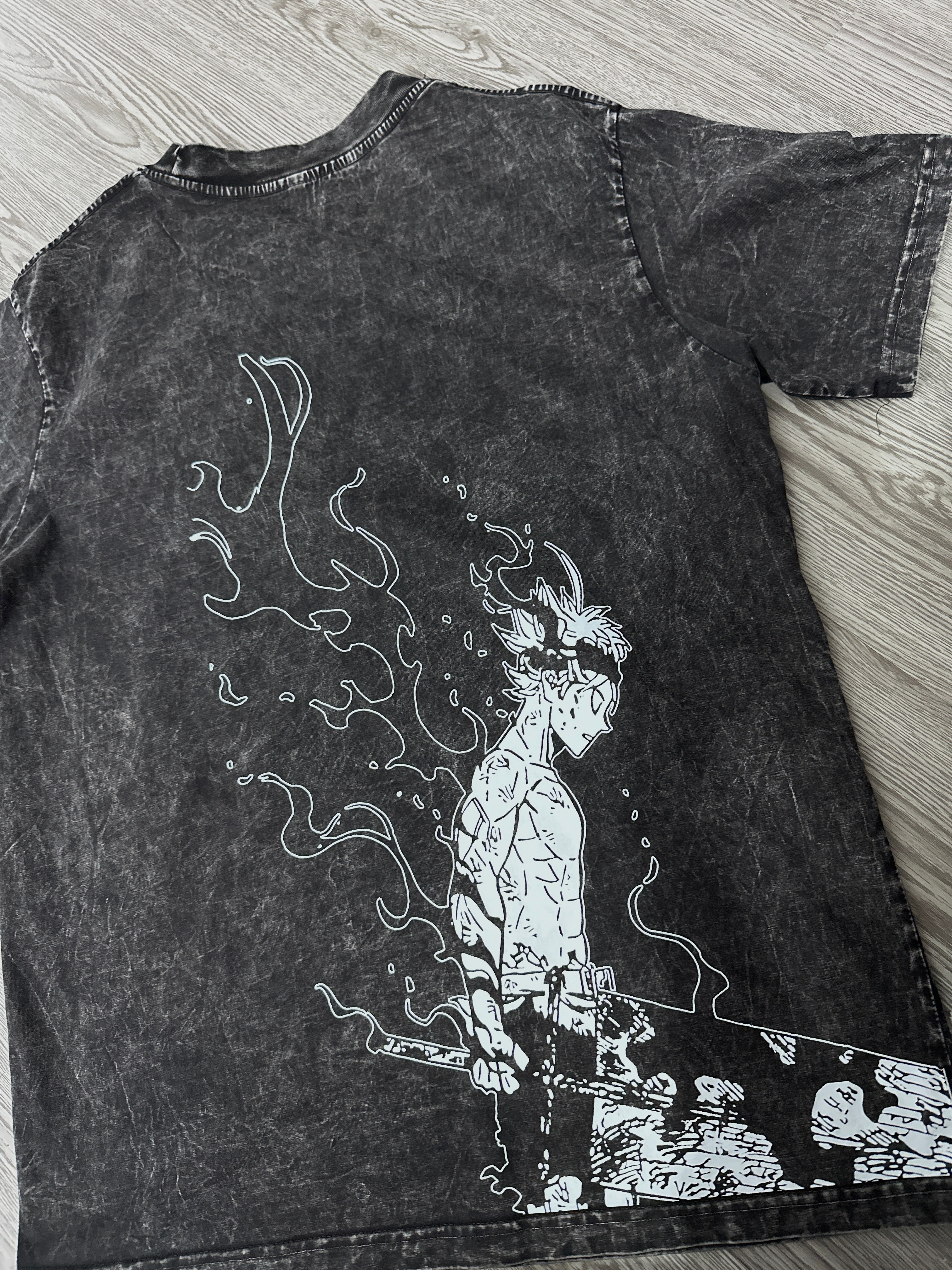 Black t-shirt with white graphic design on a wooden surface